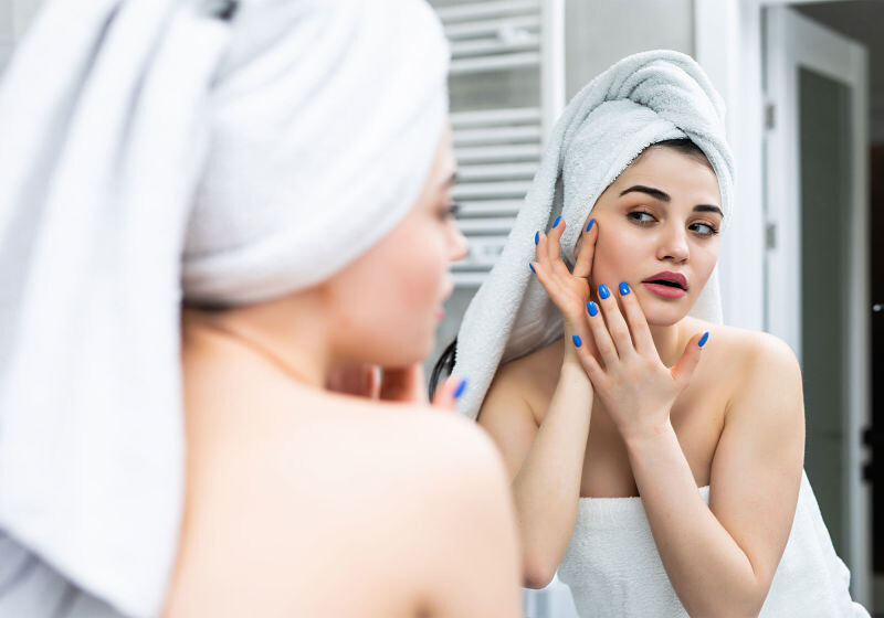 mulher com toalha na cabeça verificando manchas no rosto mulher com toalha na cabeça verificando manchas no rosto
