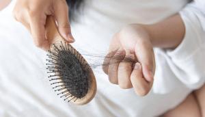 mulher tirando fios de cabelo da escova